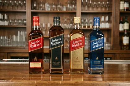 Gamme complète de whiskies Johnnie Walker alignés sur un comptoir de bar en bois poli, du Red Label au Blue Label